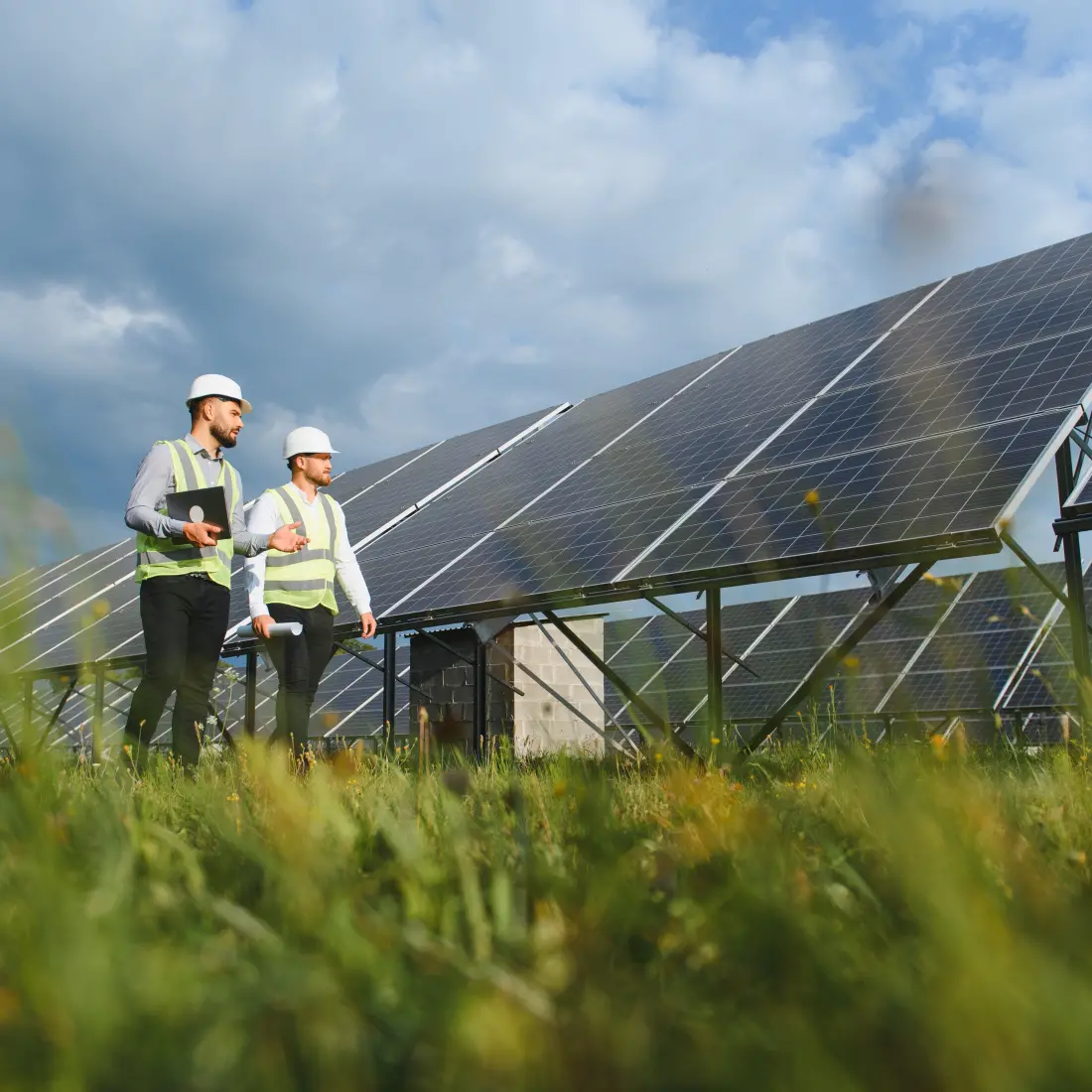 On-site solar engineering inspection featuring two professional consultants using tablets and blueprints to verify utility-scale PV system layout and terrain-following trackers.