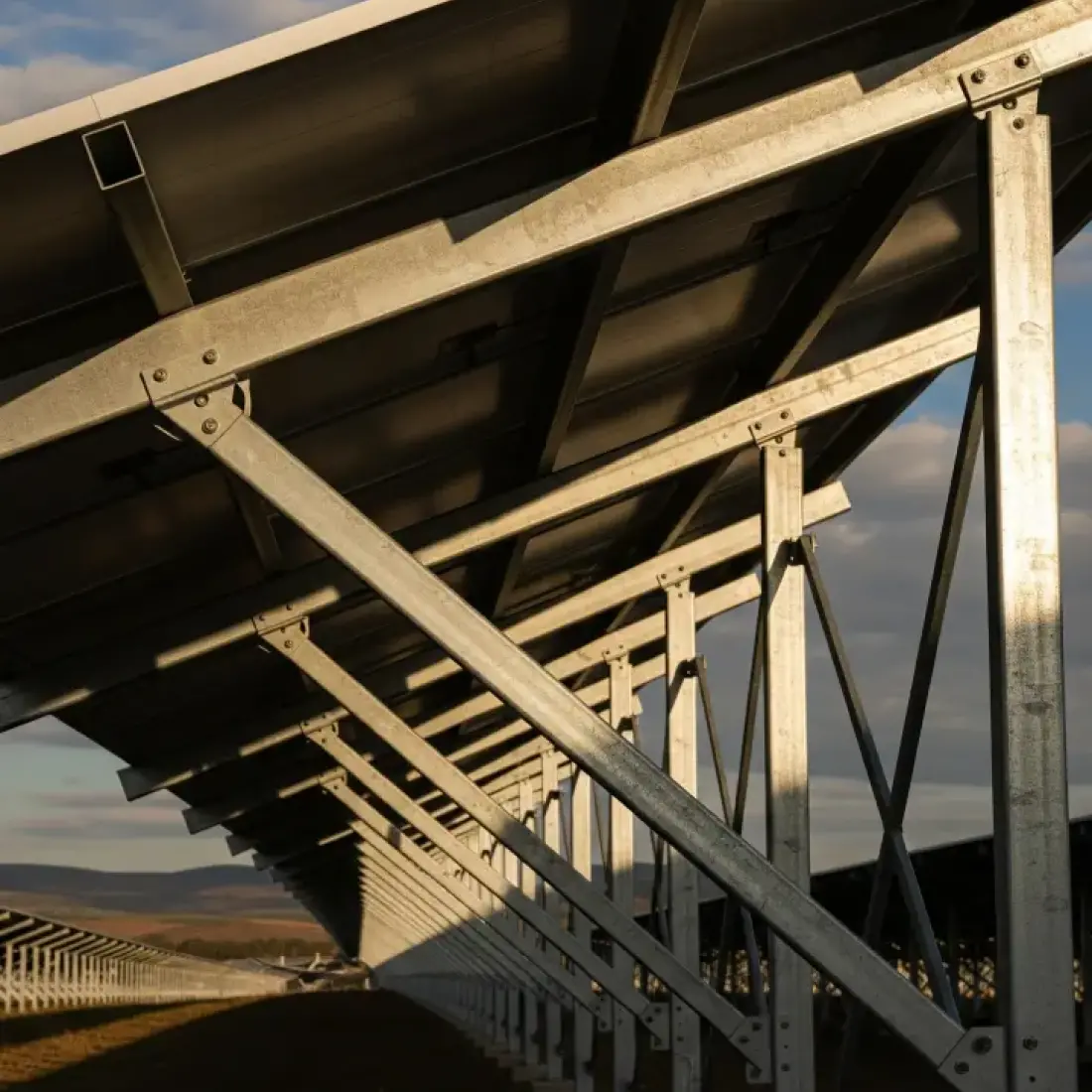 Photography of the fixed-tilt structure of a solar panel array in a solar farm.